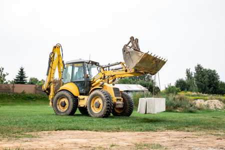 Wheel loader. Excavator install the foundation blocks into a trench. Retaining wall building. Construction site. Workers manage installation. Full HD footage video. Semkovo, Belarus - September 3, 2021.のeditorial素材