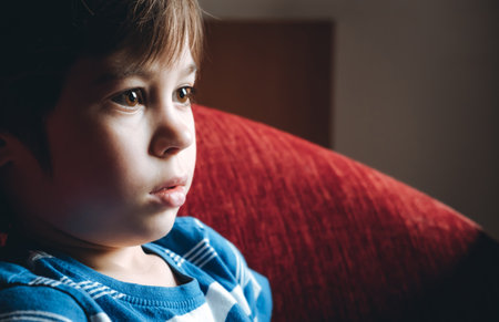 Beautiful brown eyes of 6 year old boy looking at screen close-up. Child is watching TV, cartoons or video too long. side view. The concentrating kid. play computer game. vision load. Attention.の写真素材