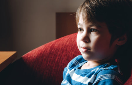 Beautiful brown eyes of 6 year old boy looking at screen close-up. Smiling child is watching TV, cartoons or video too long. side view. The concentrating kid. play computer game. vision load. Attention.の写真素材