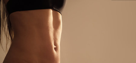 Hot girls. Sexy female stomach close-up. Belly dance of a caucasian woman. Slim waist model. copyspace. Erotically in bed. Line silhouette of naked body. sensual erotica. Tanned ladies skin. Navel.の写真素材