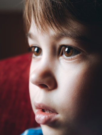 Tired eyes of 6 year old boy looking at screen close-up. Child is watching TV, cartoons or video too long. side view. open mouth. The concentrating kid. play computer game. vision load. Attention.の写真素材