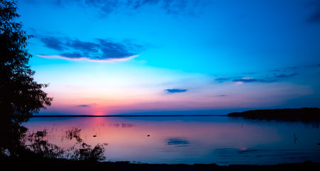 Beautiful pink sunset above the lake. Blue sky with clouds. last ray. Seascape. Calmwater. natural background. nature landscape. summer time travel. warm evening concept. no people. Morning.の写真素材