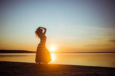 Silhouette of a full length woman posing on sea beach at sunset. Profile of sexy body. seascape background. Morning time walk. copyspace. happy person. Summer vacation. Model photo. Happiness.の写真素材