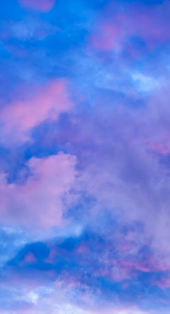 cloudscape up view. Blue sky with pink and purple cumulus clouds in the evening at sunset. vertical cloud wallpaper. natural background for design. Magic beauty in nature. copyspace. Morning colors.の写真素材