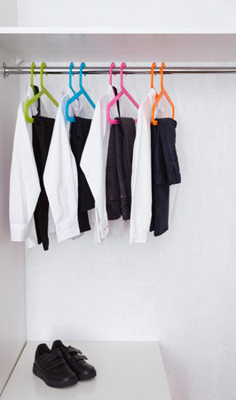 Boys school uniform on hanger. Kid clothes for education. Classical style of black and white colors. Trousers, shirts and shoes in wardrobe. 1 September. Pupil style.の写真素材