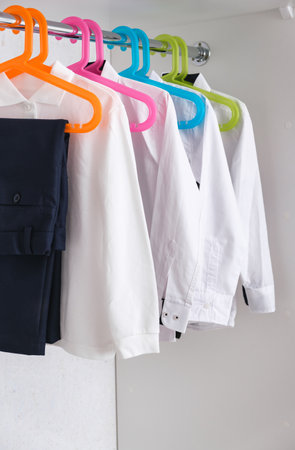 Boys school uniform on hanger. clothes for education. Classical style of black and white colors. Trousers and shirts in wardrobe. 1 September. Pupil style.の写真素材