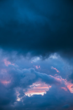 Dark blue sky clouds with pink holes. Storm weather. Beauty in nature. Twilight, golden hour. Thunderstorm. Details of evening sunset. Natural abstraction. Peace concept. Panoramic landscape view.の写真素材
