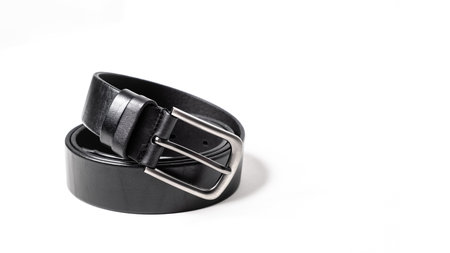 Twisted black leather belt with matted metal buckle isolated on white background. Fastened...