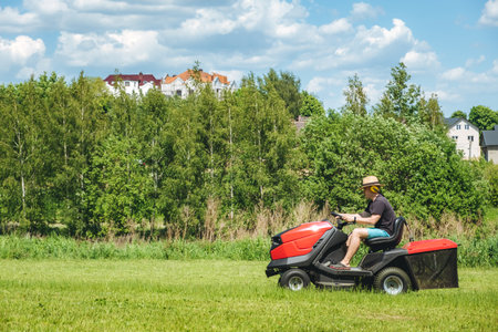 Man on lawn tractor mowing lawn on backyard. The red rider. The lawnmower tractor. High quality 4k footage.の写真素材