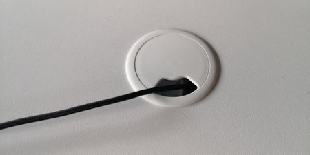 Hole for electric wire and cable on computer desk. With wire. Furniture on the table. White color. Top view. High quality photo.の写真素材