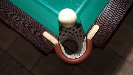 Playing Russian billiards on a green table. A white ball rolls into the corner pocket. Stop one step...
