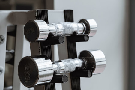 Dumbbell Rack in Fitness Gym close-up. Set of chrome steel dumbbells of different weight. Sporting equipment for strong muscles. Sport shop. Club membership.の写真素材