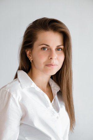 Young smiling confident business woman wearing white top shirt casual clothes looking camera isolated on gray background studio portrait. Vertical shot. Lifestyle concept. Professional office worker.の写真素材