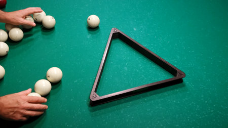 The player puts billiard balls into a triangle on a green pool table. Preparing the pyramid for the new game. Pastime playing sport hobby.の写真素材