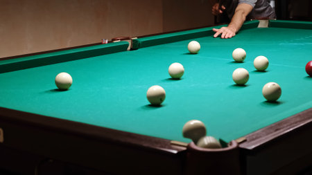 Playing Russian billiards on a green table. Billiard player hits the white ball. Good goal. Successful attempt. A great game. Hobby pastime. Corner pocket side view close-upの写真素材