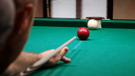 Russian billiards on a green table. A player hits the red ball with a cue and pockets white one into middle side pocket. A successful shot. Pastime at home playing sport game hobbyの写真素材