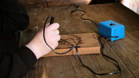 Burn out the picture. An artist drawing on a wooden plank with pyrograph. Wood burning ASMR creative hobby. Art class workshop. Creative activity. Highの写真素材