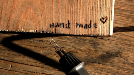 Burned out the inscription Handmade. Woodburning or pyrography. Drawing on a wooden plank with pyrograph. Wood burning creative hobby. Art class workshop. Creative activity. Highの写真素材