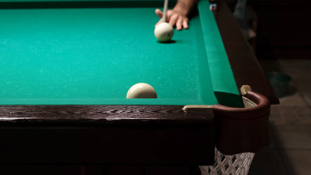 Russian billiards on a green table. American billiard. The player hits the white ball with a cue and rolling another into thecorner pocket. Successful shot. Pastime at home playingの写真素材
