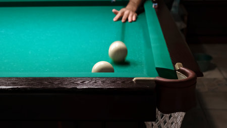 Billiards on a green table. The player hits the white ball with a cue and rolling another into the...