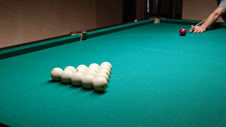 Start of the game, first move. Russian billiards on a green pool table. A player hits the red ball...