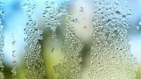 Water Drops on a glass. Dripping rain drops textured background. Close up of misted window with droplets draining down. Increased air humidity. Rainy weather. Blue green colorsの写真素材