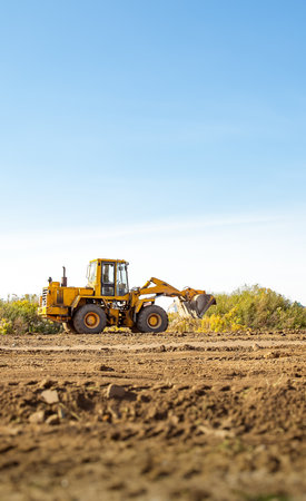 Yellow bulldozer at a construction site. Big wheel excavator leveling and clearing the land plot...