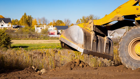 Yellow bulldozer at a construction site. Big wheel excavator leveling and clearing the land plot side view. Moving earthworks soil. Copy space. Building area. Special transportの写真素材