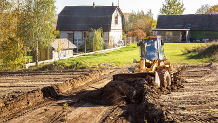 Yellow bulldozer at a construction site. Big wheel excavator leveling and clearing the land plot side view. Moving earthworks soil. Copy space. Building area. Special transportの写真素材