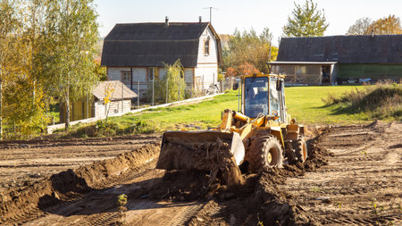 Yellow bulldozer at a construction site. Big wheel excavator leveling and clearing the land plot side view. Moving earthworks soil. Copy space. Building area. Special transportの写真素材
