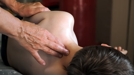 The masseur is massaging the shoulder and neck of the child. The therapeutic lymphatic drainage...