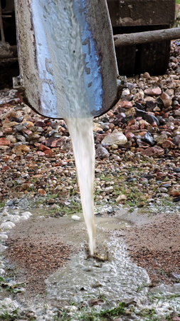 Water flows down the chute of a concrete mixer. Washes the concrete mixer after use. Washing away...