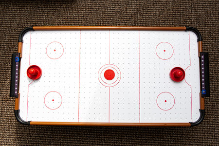 Subject shot of air hockey game table close-up. The portable table hockey includes plastic hockey paddles, a mini puck and score keepers. Hobby game background. Backdrop with copyの写真素材