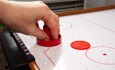 Hand ready to hit with paddle on puck. The portable table hockey includes plastic hockey paddles, a mini puck and score keepers. Hobby game background with copy space. High quality.の写真素材