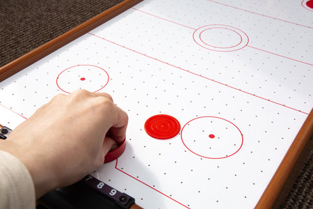 Hand ready to hit with paddle on puck. The portable table hockey includes plastic hockey paddles, a mini puck and score keepers. Hobby game background with copy space.の写真素材