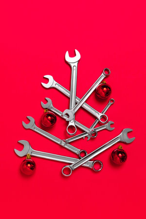 Christmas tree made of wrenches decorated with balls on a red background. New Year banner with tools. Postcard with place for greeting text for happy new year with industrialの写真素材