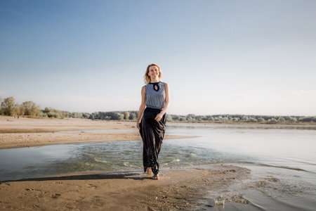Young happy freedom and independent woman walking by sandy beach along the seaside. Front view. Good feeling. Active lifestyle. Summertime traveling. Summer vacation. No problemの写真素材