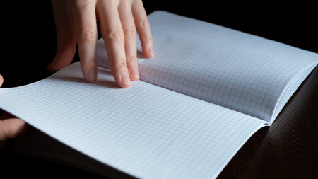 Female hands Flipping new notebook pages. Fast flicking of paper checkered sheets. View browsing. Search of note. Pleasant tactile sensations and stress relief. High quality photo.の写真素材