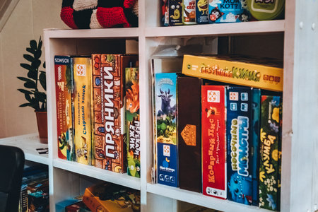 July 27,2024 Bereza, Belarus: Close up board game collection stacked on a shelf. Cheese castle, gingerbread, dragons, zombies in house, treacherous fox, sock monsters, flower bedのeditorial素材