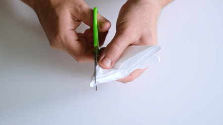Man cuts a snowflake out of a paper napkin with scissors. Making paper crafts. Fine motor skills....