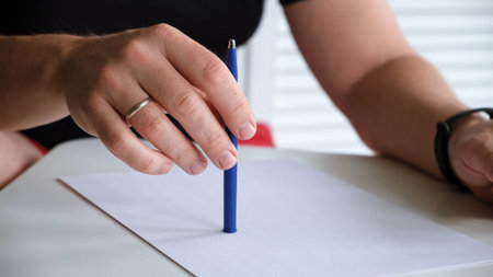A man tapping a pen on a table with a blank sheet of paper. The concept of lack of ideas, problems,...
