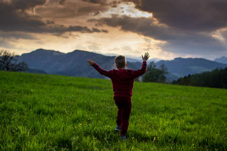 little boy runs in the rays of the sunset, hiking in the mountainsの写真素材