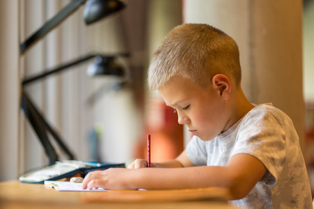 Schoolboy doing homework at a table in the city library.