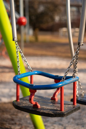 Childrens swing made of metal and plastic on the playground of a city parkの写真素材