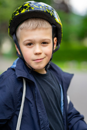 Photo of a smiling boy in a helmet on the street with a scooter.の写真素材