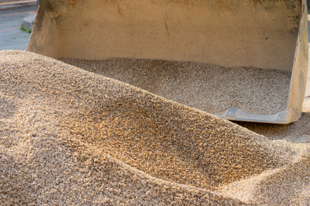 Excavator bucket picks up crushed stone for road repair.の写真素材