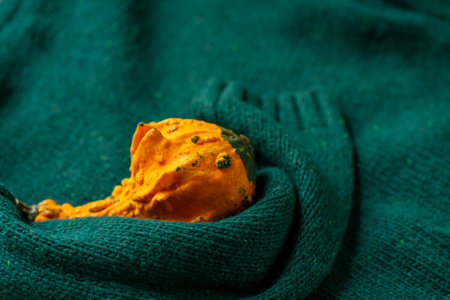 Orange pumpkin near a stack of knitted sweaters on a knitted blanket.の写真素材