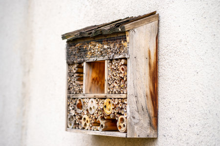 View of an empty insect hotel hanging on a stone wall.の写真素材