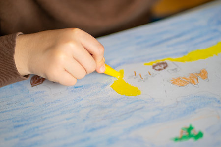 View of childrens hands drawing an island in the sea with oil pencils