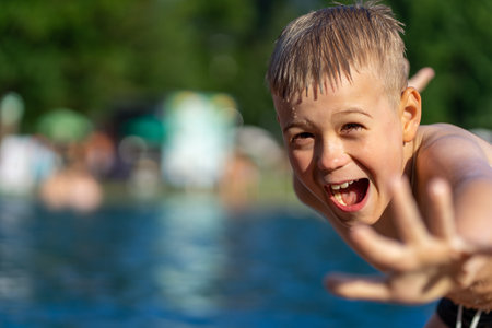 Laughing boy has fun and actively spends summer leisure time in the outdoor poolの写真素材